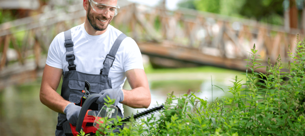 Man trimming hedges with an electric trimmer